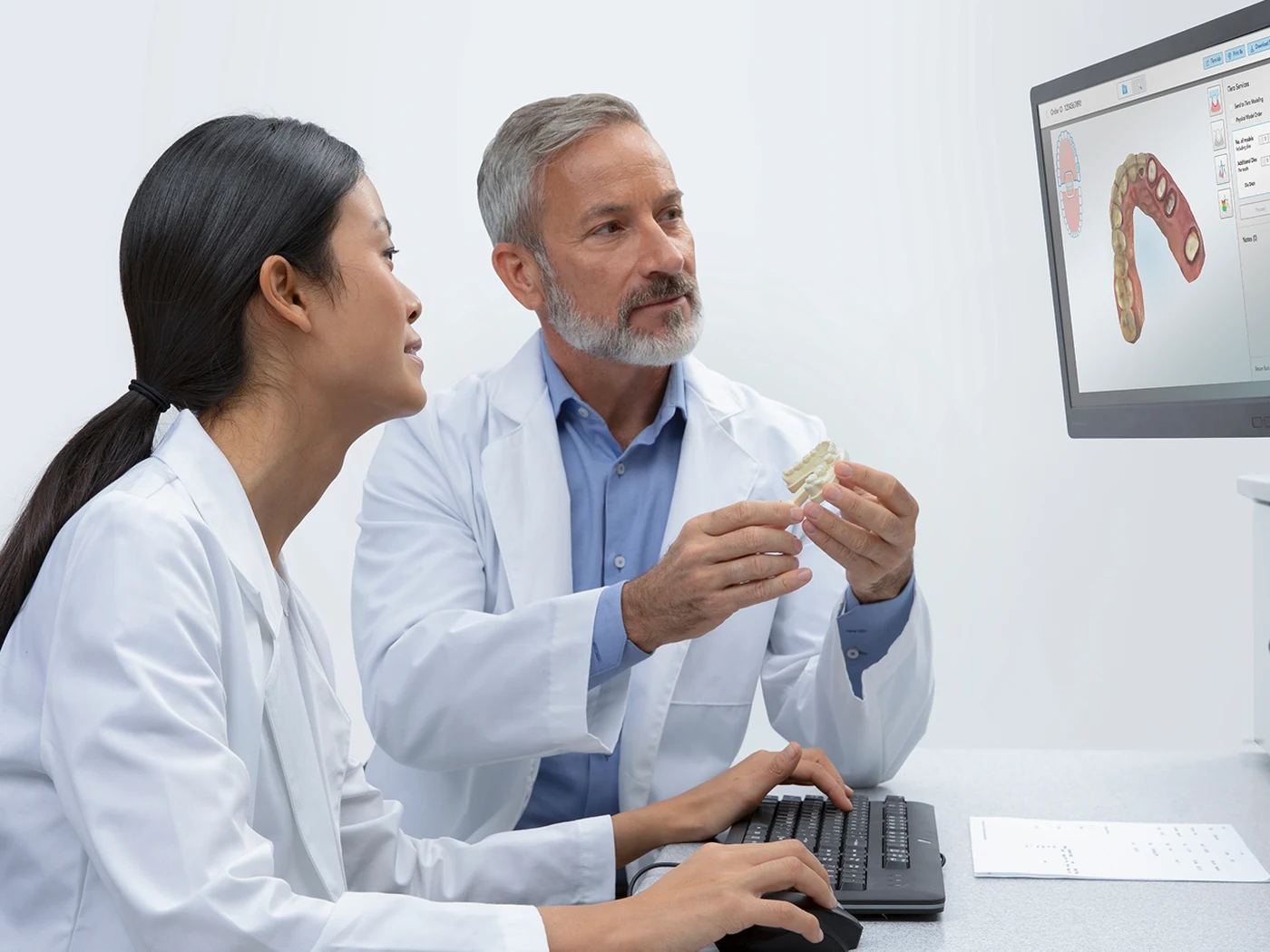 Dentistas analisam o modelo 3D de uma arcada na tela do iTero